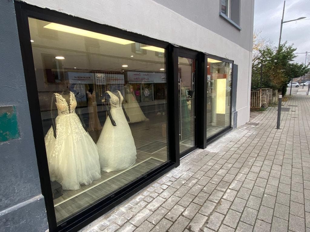 Devanture de magasin en aluminium noir avec vitrines et porte coulissante, réalisée par REM Fermetures